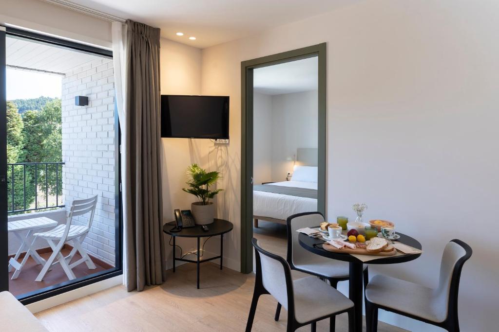 a room with a table and a bed and a balcony at Hotel H4 Cangas 3 Superior in Cangas de Morrazo