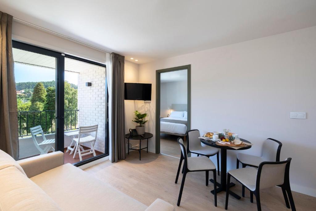 a living room with a bed and a table with chairs at Hotel H4 Cangas 3 Superior in Cangas de Morrazo