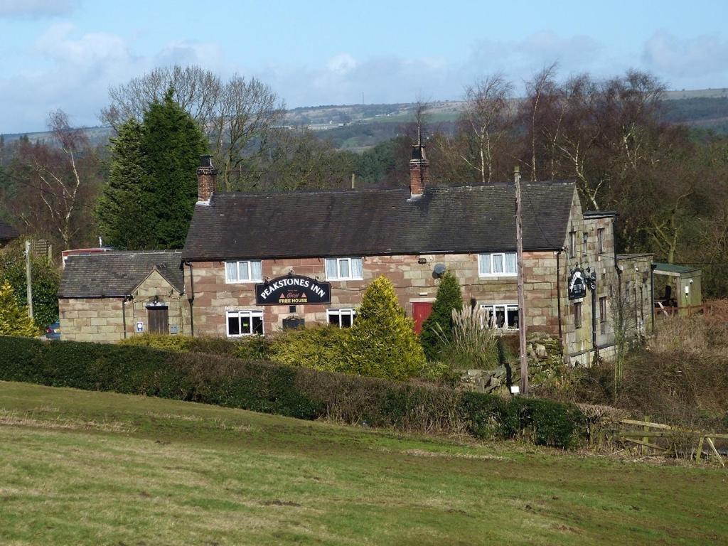 an old stone building in a field next to a field at Peakstones Inn in Alton