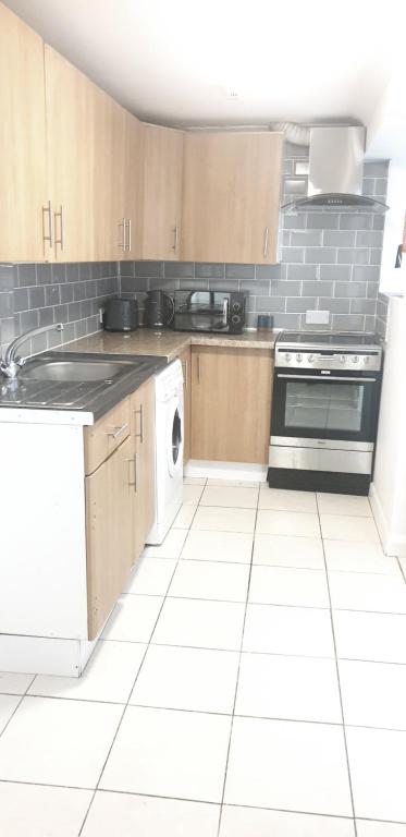 uma cozinha com armários de madeira e piso em azulejo branco em Gravesend 1 Bedroom Flat 2 Min Walk to Station & Town Centre - longer stays available em Kent