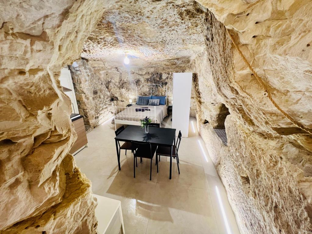 una sala da pranzo in una grotta con un muro di pietra di Murika a Modica