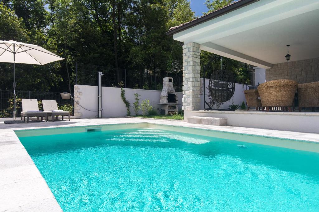 een zwembad in een achtertuin met een parasol bij Casa Maya Deluxe Appartment with a pool in Opatija