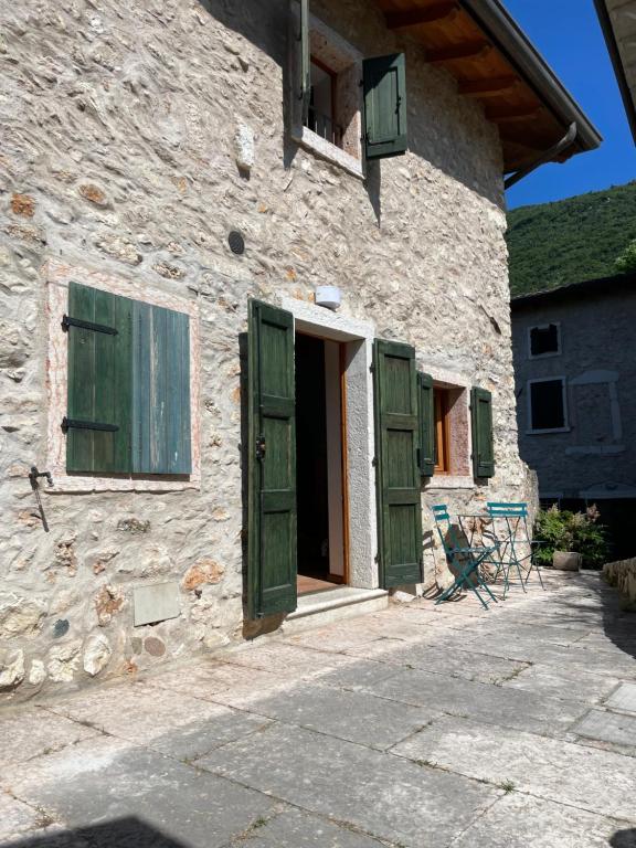 ein Steingebäude mit grünen Türen und einem Fenster in der Unterkunft Ari’sNest in Caprino Veronese