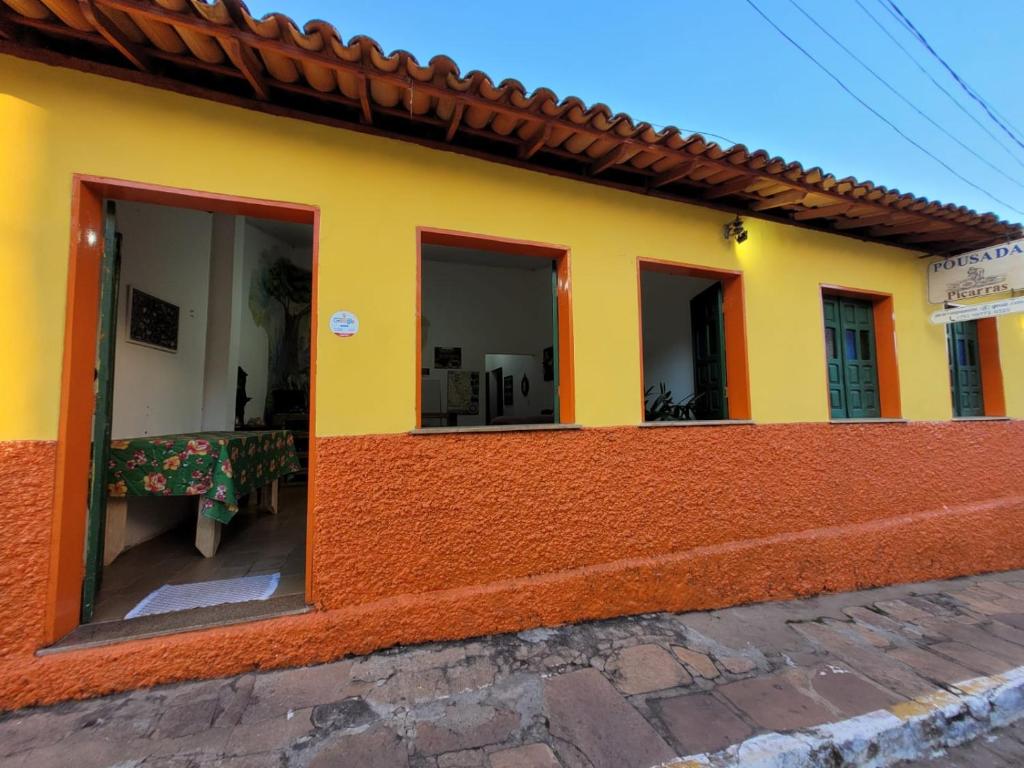 a yellow and orange house with a table outside at Pousada Piçarras - Centro Histórico in Lençóis