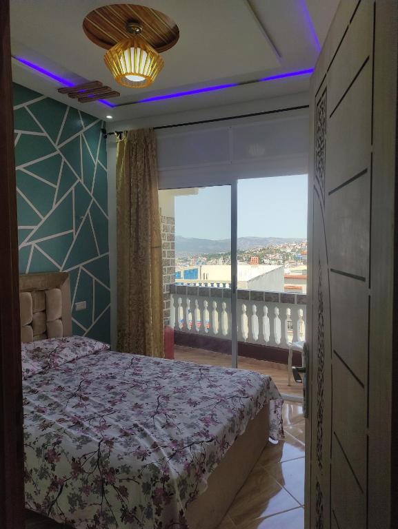 a bedroom with a bed and a large window at Rabia ahayek in Chefchaouen