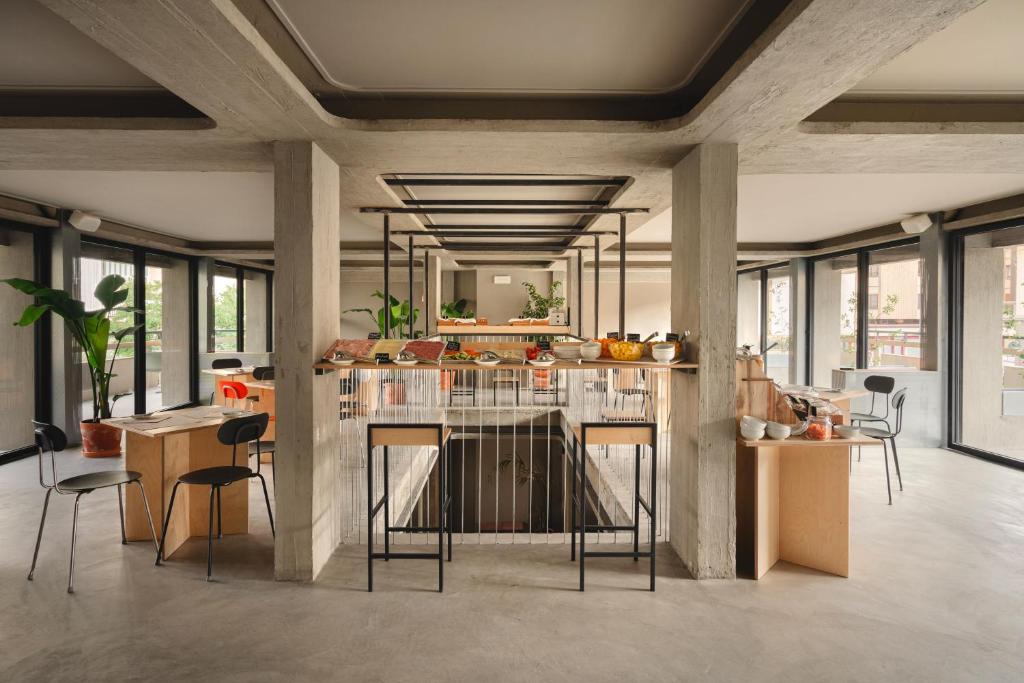 a kitchen with a counter with chairs and tables at 'RE-Dama Hostel in Florence