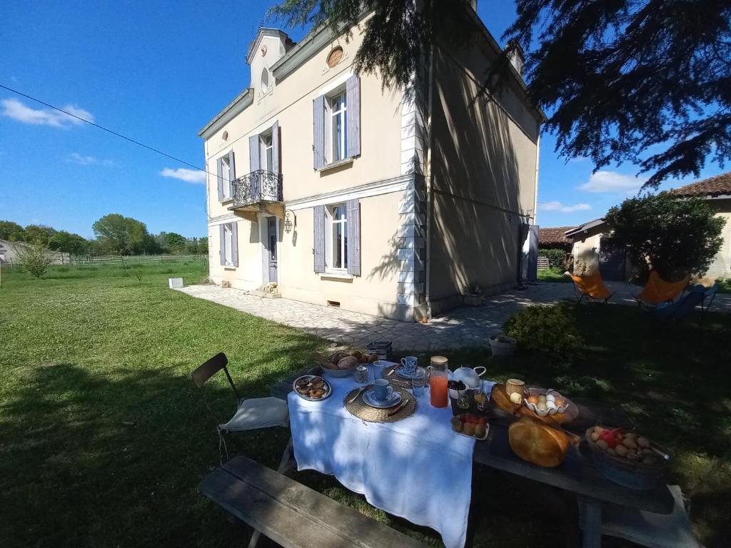 a table with food on it in front of a house at L' Embellie sur Lot in Sainte-Livrade-sur-Lot