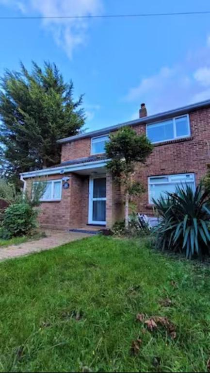 una casa de ladrillo con ventanas y un patio verde en 4 Bedroom 4 En Suite House Close to A5 & Whipsnade, en Luton