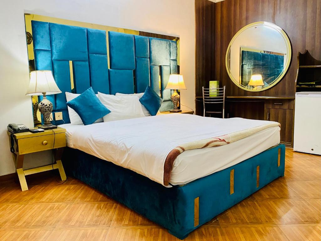 a bedroom with a large bed with a blue headboard at Fiesta Inn Hotel & Resorts Multan in Multan