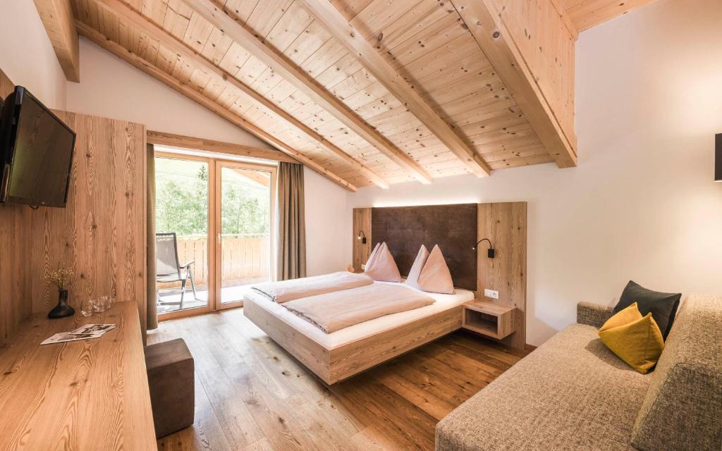 um quarto com uma cama grande e um sofá em Gasthof Jaufensteg em Racines