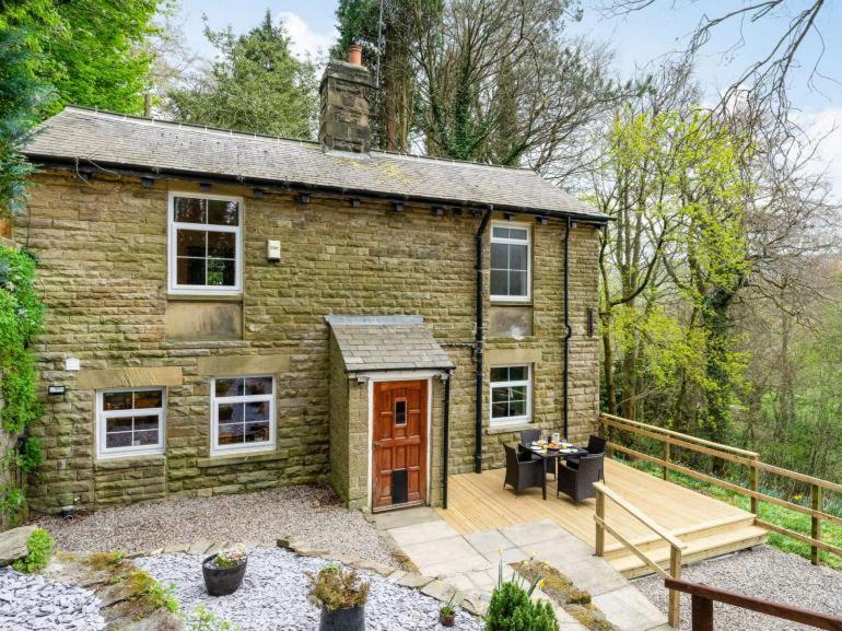 a small brick house with a wooden patio at Harefield Lodge in Pateley Bridge