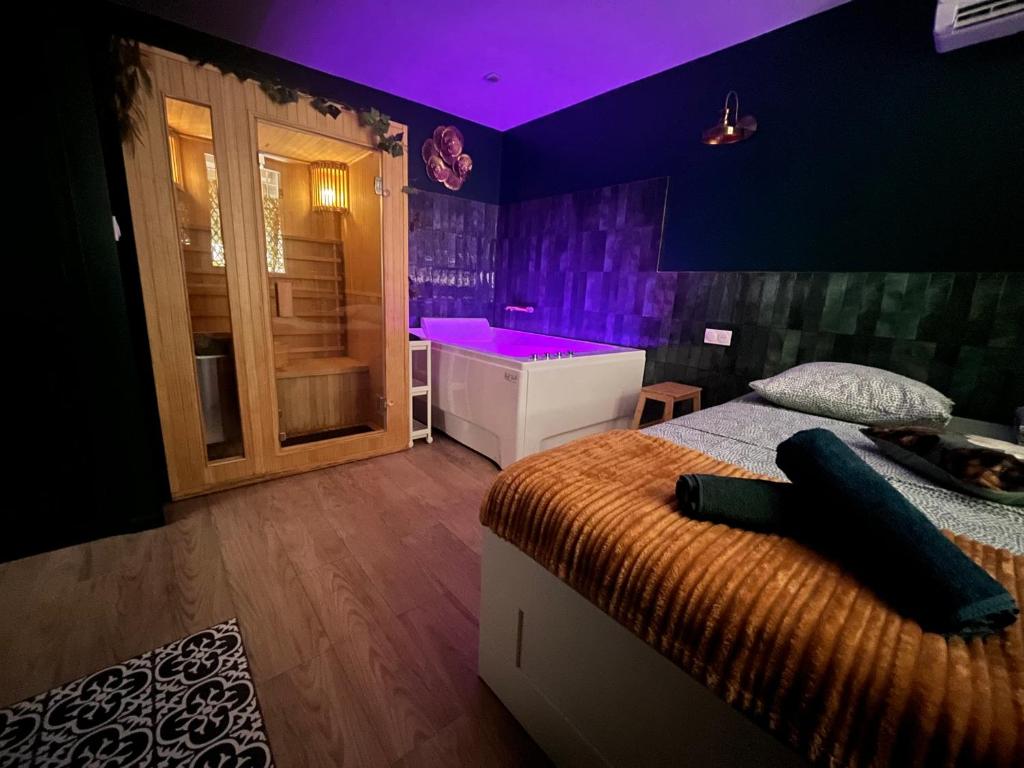 a bedroom with a bed and a tub in a purple room at Le SPEAK EASY / JACUZZI ET SAUNA in Marseille