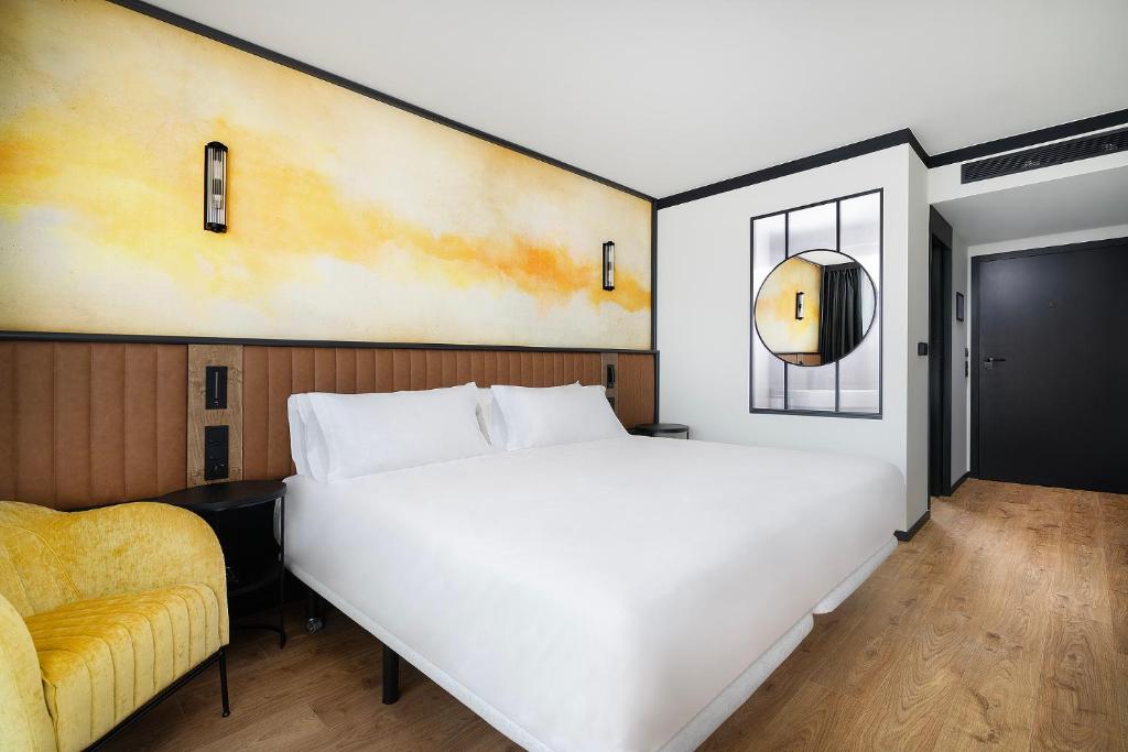 a bedroom with a white bed and a yellow chair at Barceló Warsaw Powiśle in Warsaw