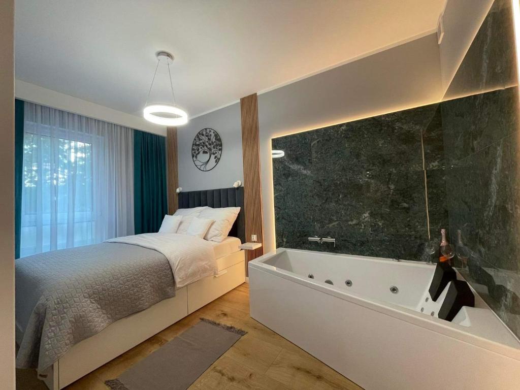 Caroline Jacuzzi Apartments في نوفي دفور مازوفييتسكي: غرفة نوم مع سرير وحوض استحمام