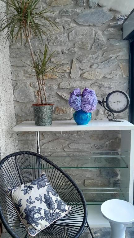 une chaise et une table avec des fleurs sur une étagère dans l'établissement Liloye, à Bagnères-de-Bigorre