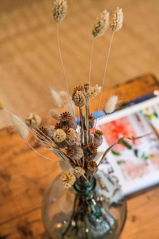 a glass vase with dried flowers in it on a table at Maison Arthur in Aigues-Mortes