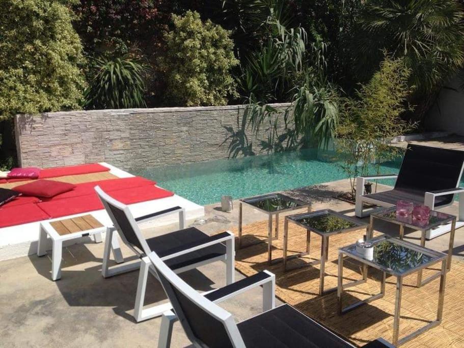 a patio with chairs and a bed and a pool at Narcisses House in La Marsa