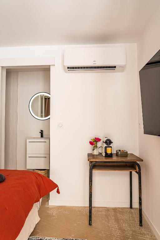 a bedroom with a bed and a table with a fan at Maison Arthur in Aigues-Mortes