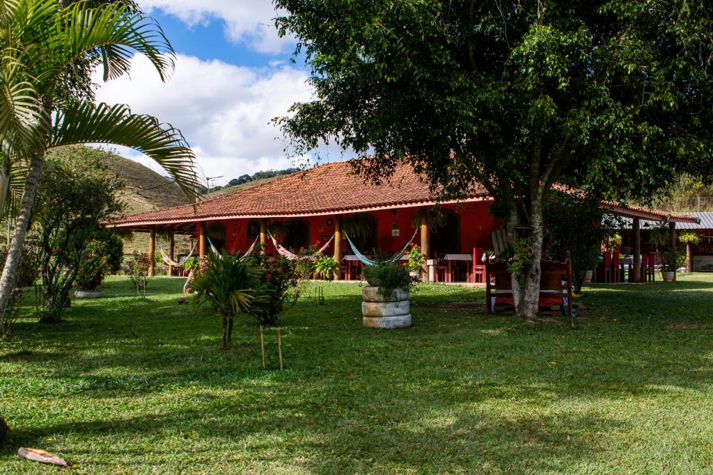 ein Resort mit einem roten Gebäude mit einer Palme in der Unterkunft Recanto da roça in Conservatória