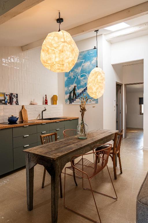 a kitchen with a wooden table and chairs and two lights at Maison Arthur in Aigues-Mortes