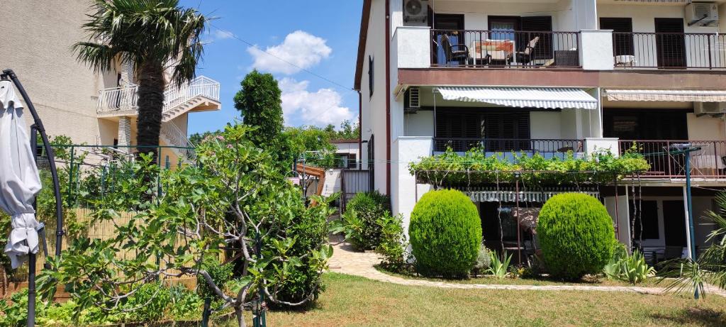 ein Apartmenthaus mit einem Hof mit Bäumen und Sträuchern in der Unterkunft Apartments Svjeta in Jadranovo