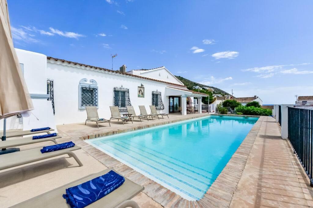 a swimming pool in a villa with chairs and a house at Villas Guzman - San Vicente in Moraira