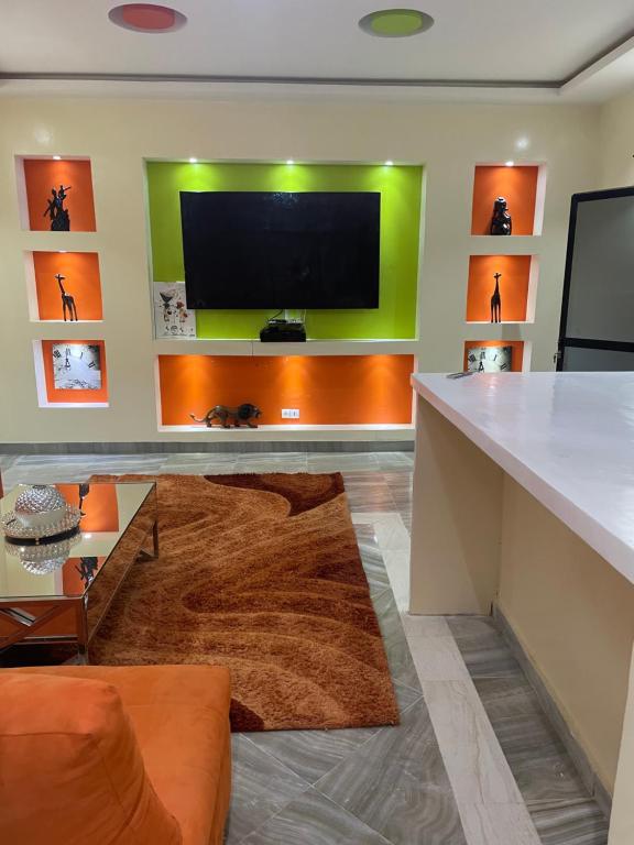 Notre Residence 27 في داكار: غرفة معيشة مع تلفزيون بشاشة مسطحة على جدار