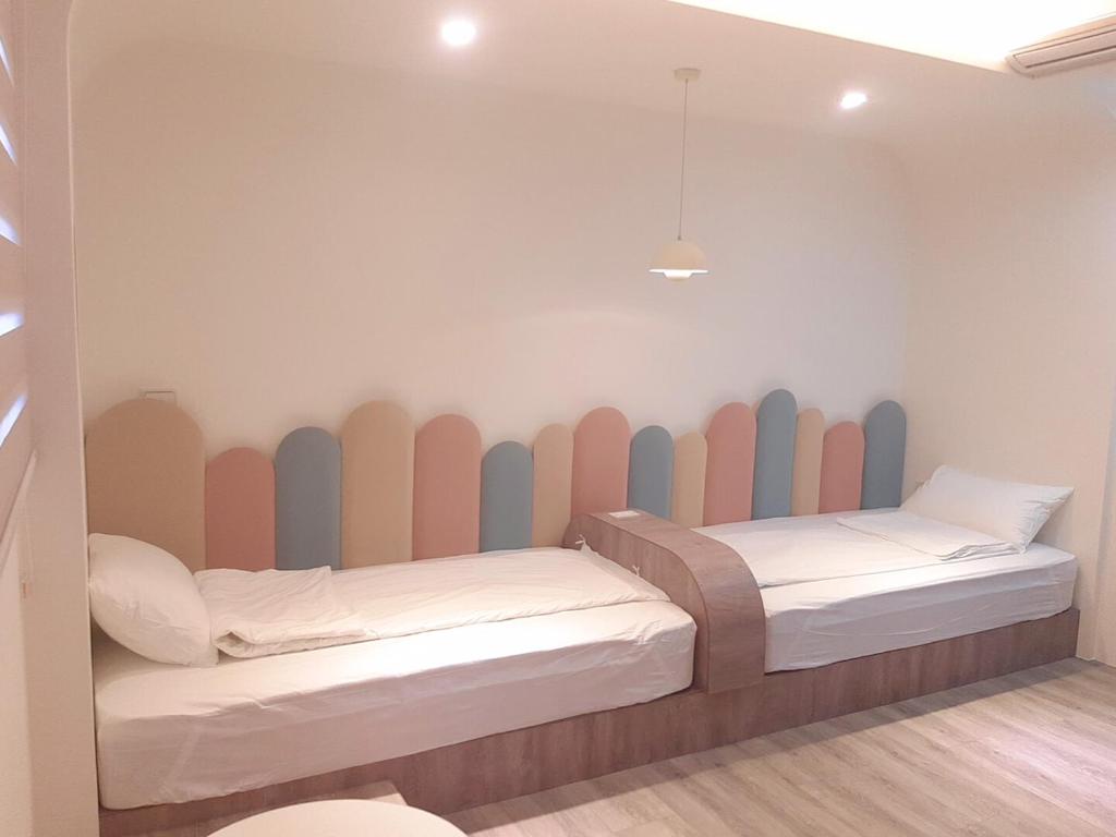 two beds in a room with a wall made of surfboards at 台東有點田民宿 in Guanshan
