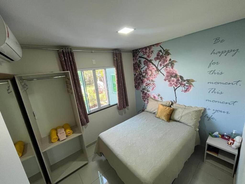 a small bedroom with a bed and a tree mural on the wall at Family Comfort, Casa residencial Aconchegante in Foz do Iguaçu