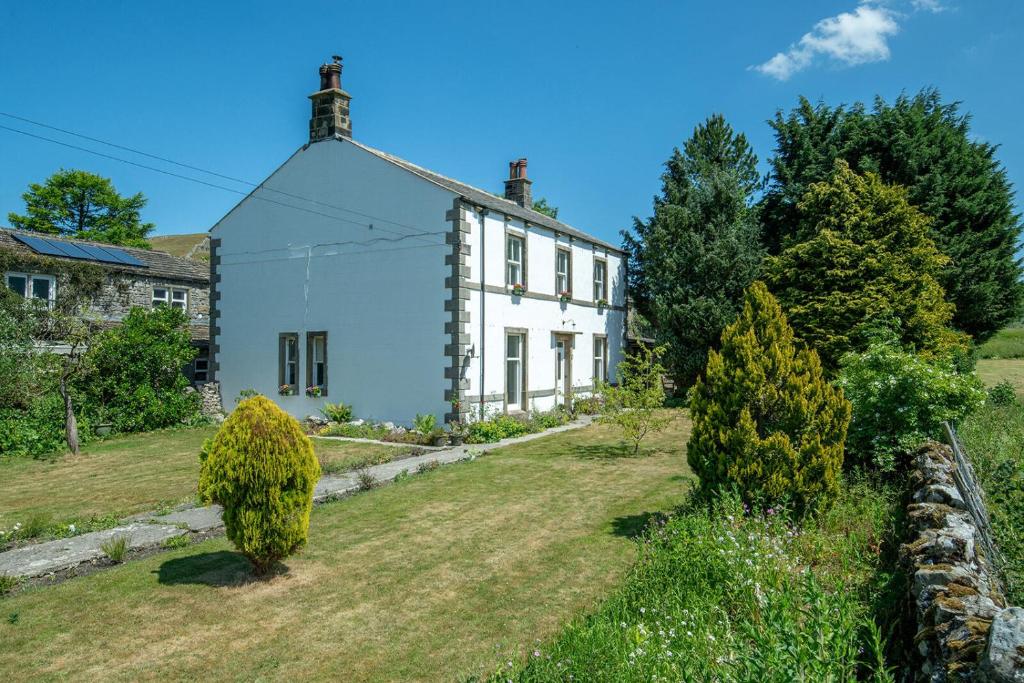 a white house on a hill with a yard at Miresfield Farm Bed & Breakfast in Malham