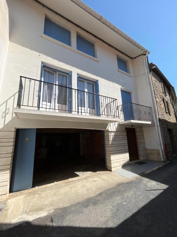 a white building with a balcony and a garage at Le mont canigou in Taurinya