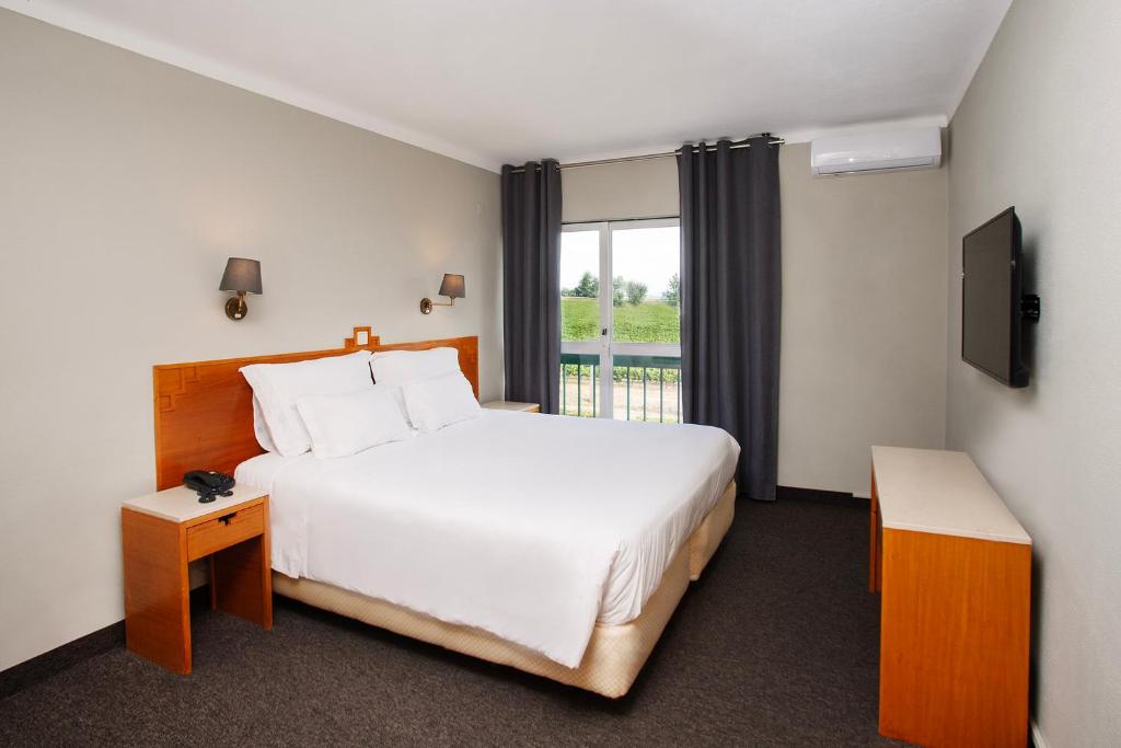 a hotel room with a large bed and a window at Estremoz Hotel in Estremoz