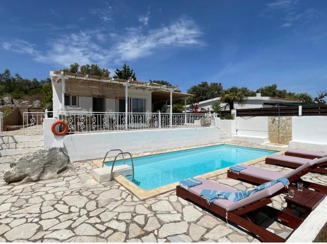 a swimming pool with lounge chairs and a house at Hestia's House in Meganisi