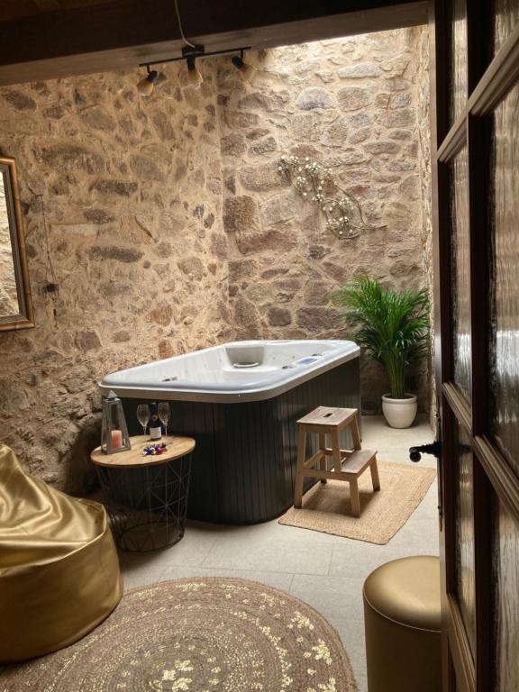 Una bañera en una habitación con una pared de piedra. en Ambar SPA. Azagalla Rural, en Casas del Abad