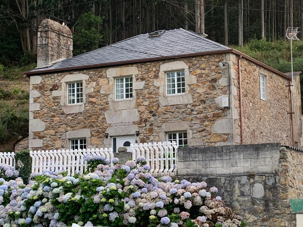 un edificio de piedra con dos bancos blancos y flores en Casa da Vizcaya, Xilloi beach, en O Vicedo