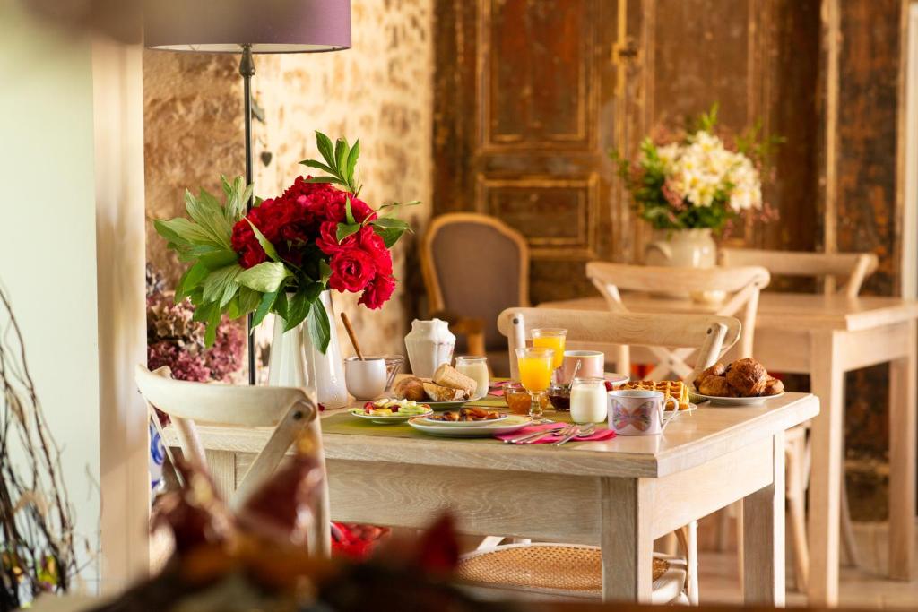 - une table avec des assiettes de nourriture et des fleurs rouges dans l'établissement Maison d'Hôtes La Maison de Léopold, à Terrasson
