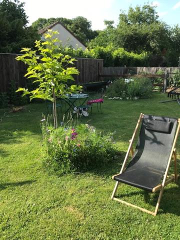 a yard with a black chair in the grass at Lou Bohème in Le Briou