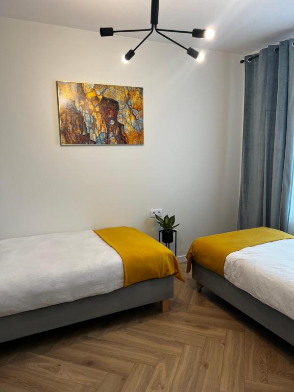 a bedroom with two beds and a painting on the wall at Apartament Szmaragdowy. in Siedlce
