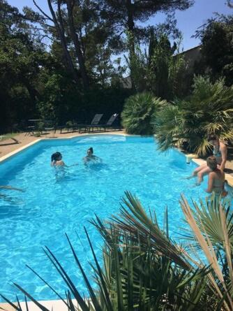 un groupe de personnes dans une grande piscine bleue dans l'établissement Villa provençale et ses grands pins, à Pernes-les-Fontaines