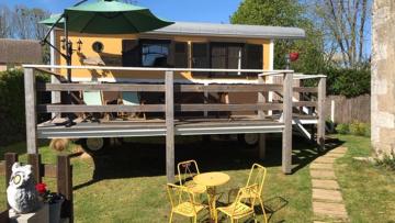 a house with a deck with a table and chairs at Lou Bohème in Le Briou