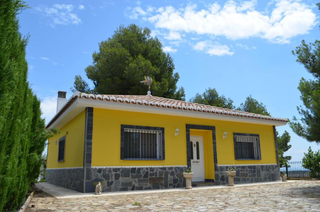 une maison jaune avec un toit dans l'établissement Casa rural en Casas de Moya 'Casa del Pino Gori', à Casas de Moya