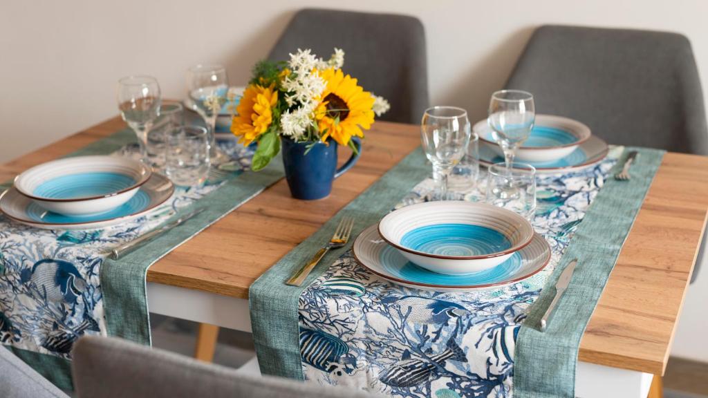 un tavolo in legno con piatti e bicchieri e fiori di Welcomely - Loft Gabbiani Cala Gonone a Cala Gonone