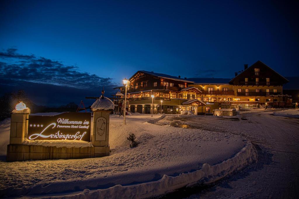 ein großes Gebäude im Schnee in der Nacht in der Unterkunft Panorama Hotel Gasthof Leidingerhof in Mondsee