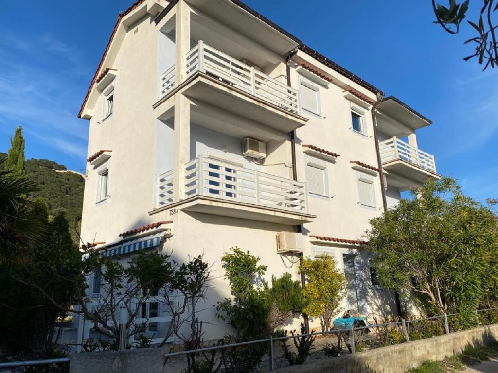 a large white building with white balconies and trees at Apartments Olea in Rab