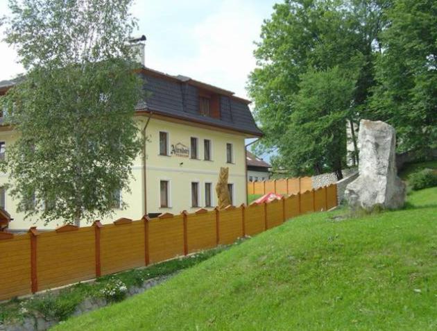 una cerca frente a una casa con un árbol en Penzion Altendorf, en Stará Lesná