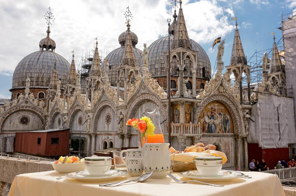 Canaletto Luxury Suites - San Marco Luxury في البندقية: طاولة مع أطباق من الطعام أمام الكاتدرائية