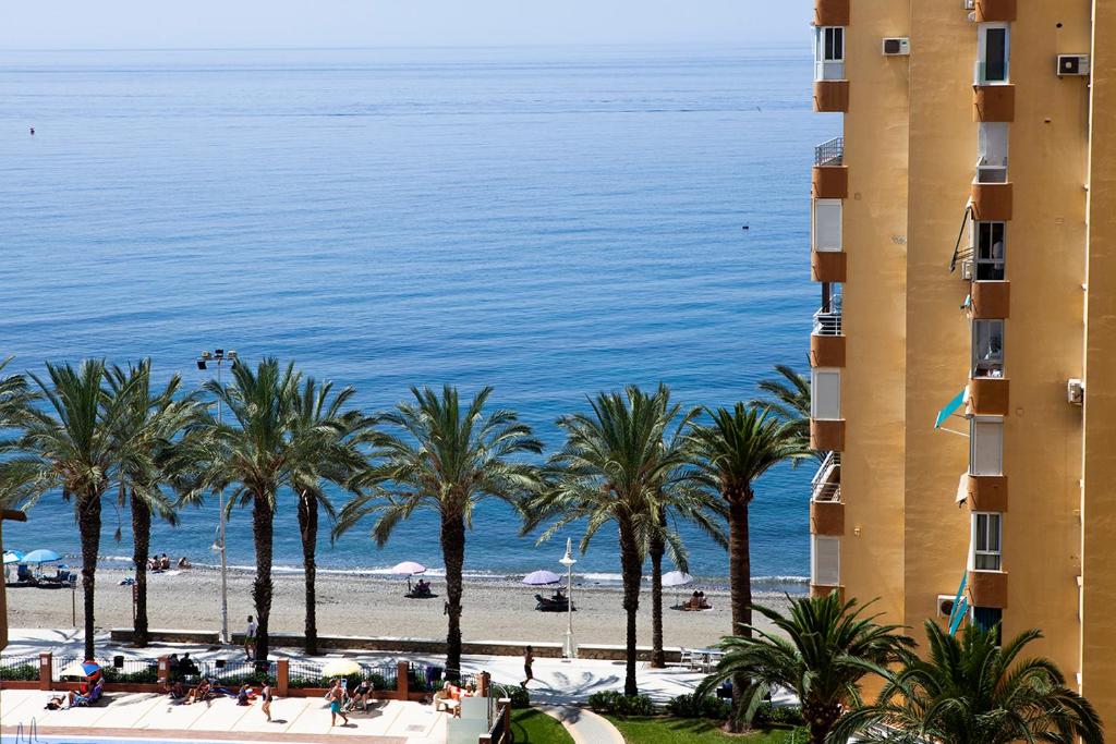 Blick auf einen Strand mit Palmen und ein Gebäude in der Unterkunft Apartment with see view in Algarrobo-Costa