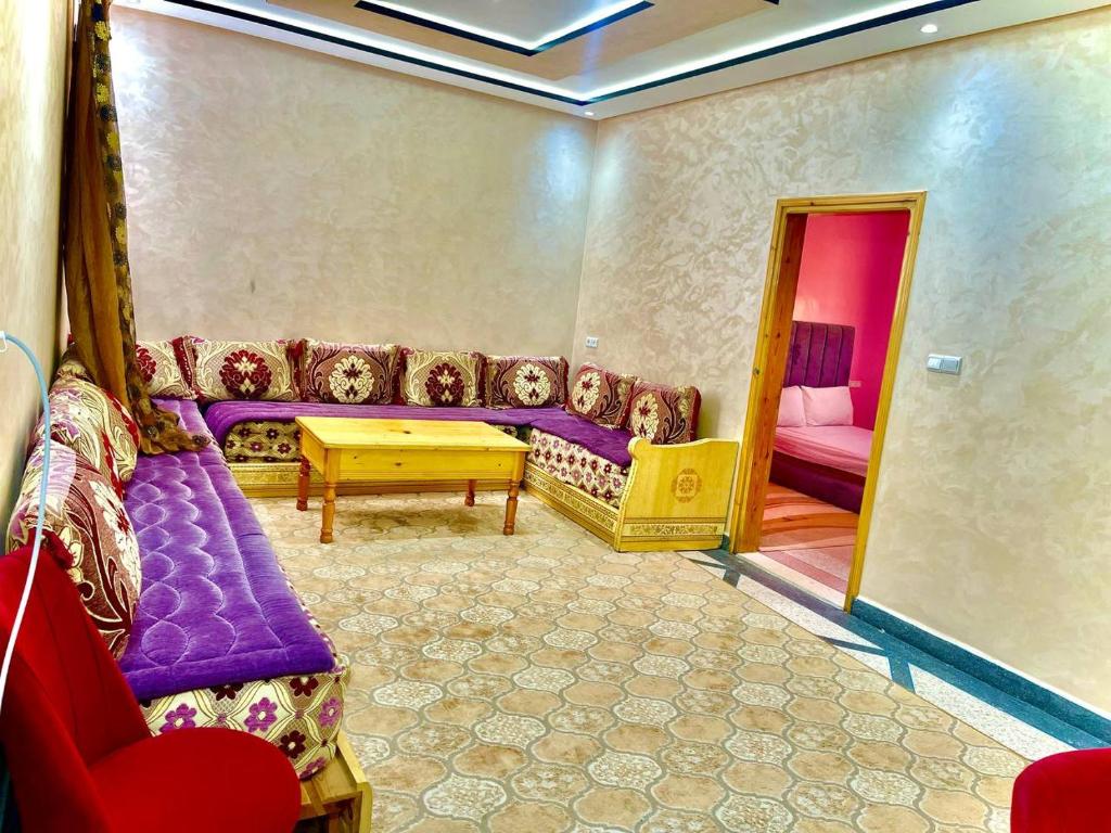 ダフラにあるRésidence Othmaneの紫色のソファとテーブル付きのリビングルーム