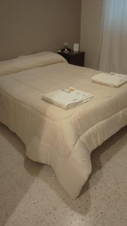 a white bed with two towels on top of it at Hotel Plaza in Coronel Suárez