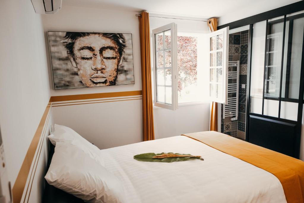 Un dormitorio con una cama blanca con una foto en la pared en LA MAISON CACHEE-BA, en La Teste-de-Buch